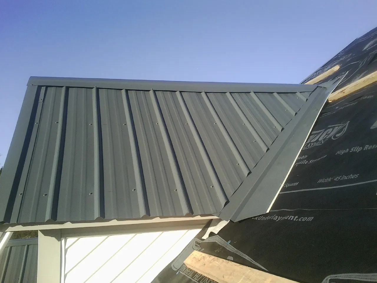 Gray metal roof panels going on over a garage gable in Bridger