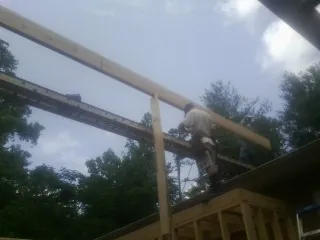 Carpenter setting a ridge beam over a new addition frame — Ice Dam Removal by Roofing Brothers in Bridger