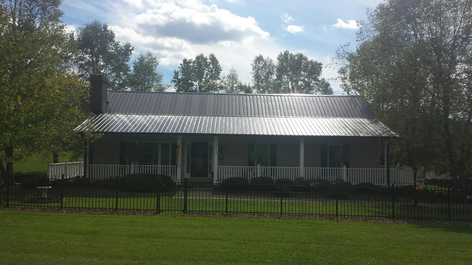 Gray metal roof on a brick ranch with a full width front porch — Gutter Guard Installation work by our crew in Bridger