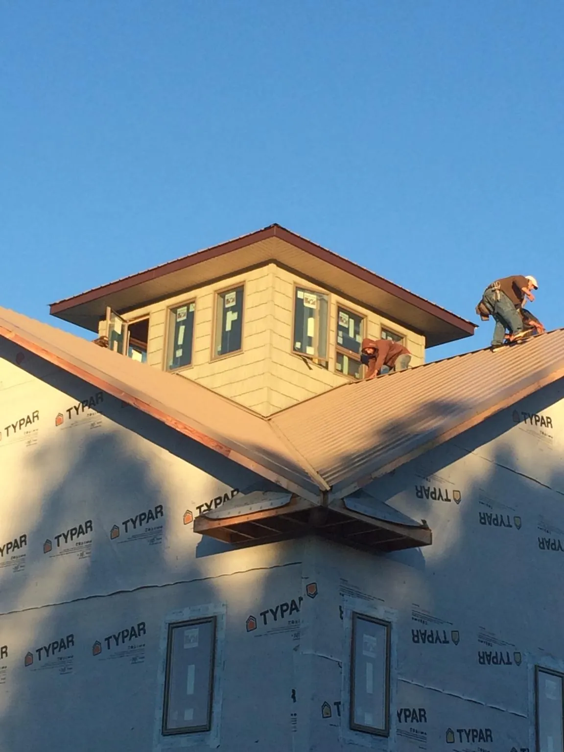 Roofers working around a rooftop cupola on a new metal roof at sunset — Roof Waterproofing in Bridger by Roofing Brothers